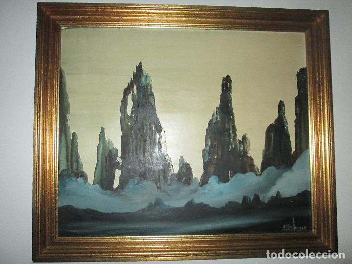 Pintura enmarcada atribuida a J. Torrecilla con agujas rocosas oscuras sobre un mar de nubes